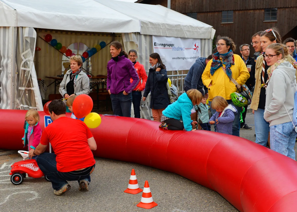 Ein Bobbycar und Kinder und Erwachsene.